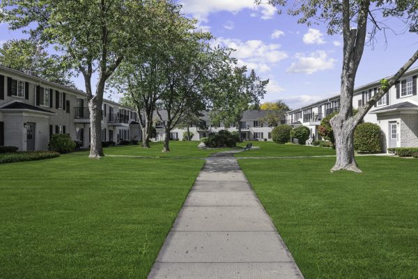 Courtyard view of suburban apartment complex with lush greenery and clear blue sky.