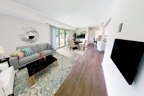 Modern living room with gray couch, decorative pillows, and large windows showcasing a bright, airy space.