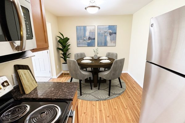 Modern kitchen-dining area with stainless steel appliances, round table, and abstract wall art.