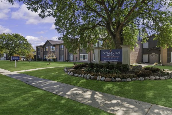 Exterior view of Twyckingham Valley Apartments with lush green lawn and pathways under a clear blue sky.