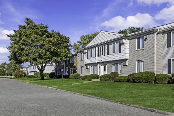 Apartment complex with lush green lawn and clear blue sky.