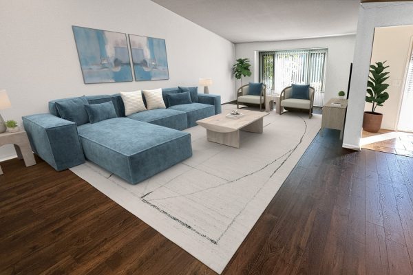Modern living room with blue sectional sofa, wooden floors, and large window letting in natural light.