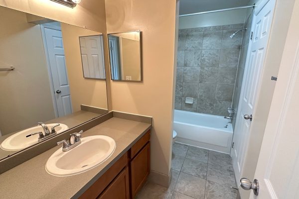 Modern bathroom with large mirror, white sink, and tiled shower. Neutral decor enhances spacious feel.