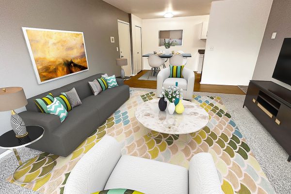 Modern living room with gray sofa, colorful cushions, abstract art, and a round marble coffee table on a patterned rug.