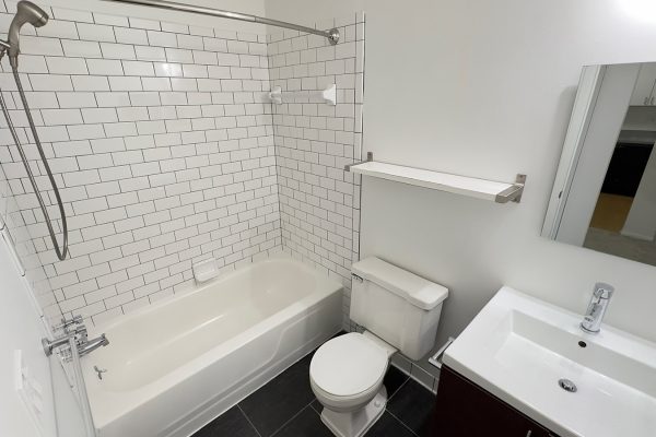 Modern bathroom with white subway tiles, tub-shower combo, toilet, and sink vanity.