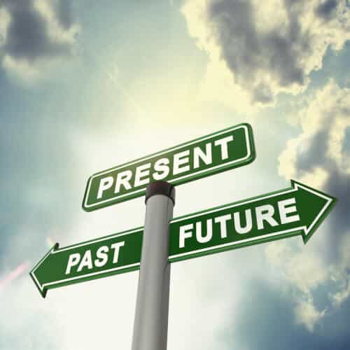 Signpost with arrows pointing to past, present, and future against a cloudy sky background, symbolizing time and direction.