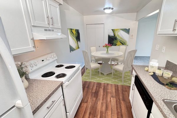 Modern kitchen with white cabinets, granite countertops, and dining area with a round table and vase of flowers.