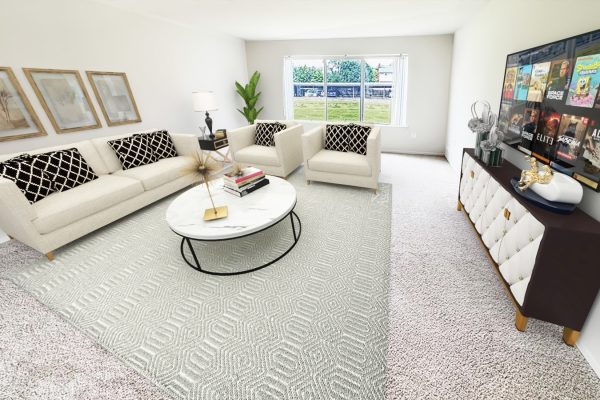 Modern living room with beige sofa, round marble table, TV, and window view. Elegant decor and neutral tones.