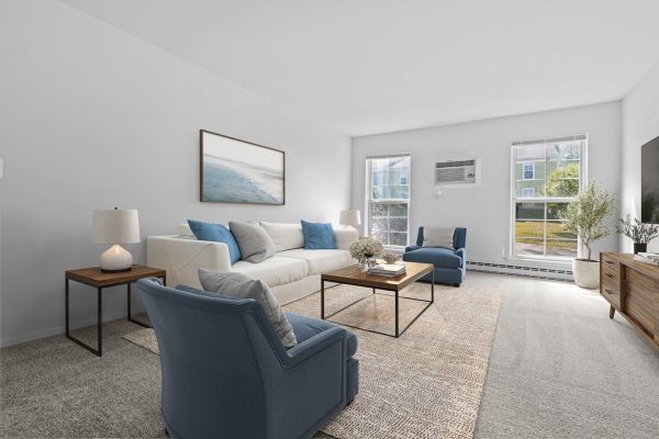 Modern living room with white sofa, blue chairs, minimalist decor, large windows, and coastal artwork.
