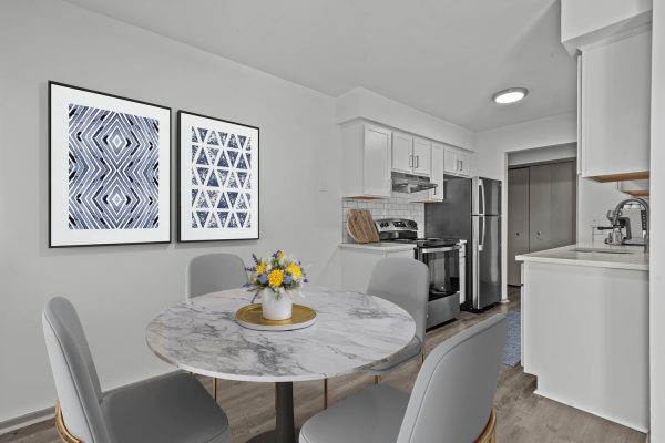 Modern kitchen and dining area with marble table, geometric wall art, and stainless-steel appliances.